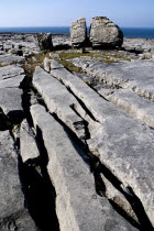 Large limestone boulder split in two surrounded by pavements and grykes.Eire European Irish Northern Europe Republic Ireland Poblacht na hEireann 2 Blue Gray Karst Sedimentary Rock Scenic