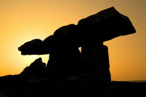 Poulnabrone Dolmen  Silhouetted against sunset. The thin capstone sits on two 1.8 metre  6 feet  high portal stones. These stones created a chamber within which the dead were placed. The people buried...