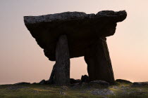 Poulnabrone Dolmen  Silhouetted against sunset. The thin capstone sits on two 1.8 metre  6 feet  high portal stones. These stones created a chamber within which the dead were placed. The people buried...