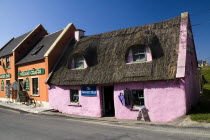 Colourful craft shops in village - one with thatched roof.Eire European Irish Northern Europe Republic Ireland Poblacht na hEireann 1 Blue Colorful History Historic Single unitary