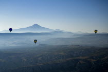 Turkey, Cappadocia, Goreme, Hot air balloons in flight over landscape, Early morning with hot air balloons in flight, Mount Erciyes in the background.