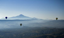 Turkey, Cappadocia, Goreme, Hot air balloons in flight over landscape, Early morning with hot air balloons in flight, Mount Erciyes in the background.