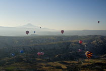 Turkey, Cappadocia, Goreme, Hot air balloons in flight over landscape, Early morning with hot air balloons in flight, Mount Erciyes in the background.