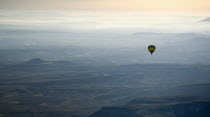 Turkey, Cappadocia, Goreme, Hot air balloons in flight over landscape, A solitary hot air balloon glides over the landscape in early morning light.