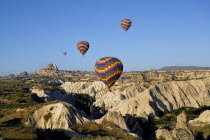 Turkey, Cappadocia, Goreme, Hot air balloons in flight over landscape, Early morning balloon flight above the town of Uchisar.