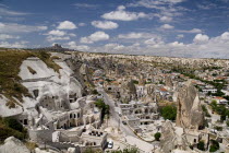 Turkey, Cappadocia, Goreme, Cave hotel with a section of the town and its minaret.