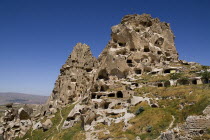 Turkey, Cappadocia, Uchisar Castle, Rock cut graves have been found inside the castle and today it has many dovecote. A person stands below the Turkish flag on top.