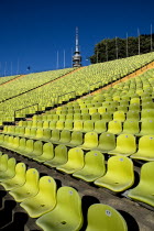 Germany, Bavaria, Munich, Olympic Stadium, The colourful green seats in the stadium with the Olympic Tower behind.