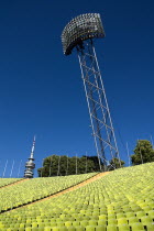 Germany, Bavaria, Munich, Olympic Stadium, The colourful green seats in the stadium with the Olympic Tower and floodlights behind.