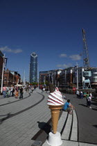 Gunwharf Quay. Tourist and shoppers walking along the canalside  with large plastic Ice Cream Cone in the foreground.Gun Wharf Blue European Great Britain Holidaymakers Northern Europe Tourism Touris...