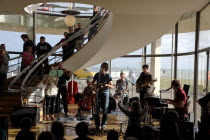 England, East Sussex, Bexhill on Sea, De La Warr Pavilion. Interior of the Art Deco Gallery and Arts Centre. Band performance under the stairwell from the Wilkomen Collective group including the Leisu...