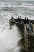 England, East Sussex, Brighton, Seafront, Tourists With waves crashing against sea defences.
