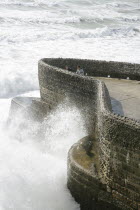 England, East Sussex, Brighton, Seafront, Tourists With waves crashing against sea defences.