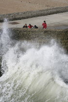 England, East Sussex, Brighton, Seafront, Tourists With waves crashing against sea defences.