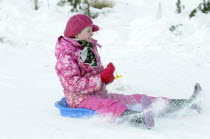 Weather, Winter, Snow, Young girl sledding down hill. Perth, Scotland.