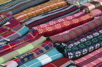 India, Goa, Mapusa, Colourful woven textiles in rolls for sale in market.