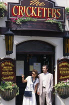 England, Brighton, East Sussex, Young couple standing outside the Cricketers public house in The Lanes one of the oldest pubs in the city dating from 1547.