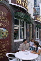 England, Brighton, East Sussex, Young couple sitting at outdoor table at The Market Inn public house in The Lanes with cups of coffee.