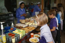 England, East Sussex, Brighton, Young girl collecting her hot meal from dinner lady ay counter in school canteen.