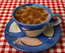 Drink, Hot, Coffee, Cup of coffee with dusted chocolate in a Majolica ceramic cup and saucer on a red and white table cloth.