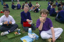 England, East Sussex, Brighton, Young boys having their packed lunches on the grass of the school playing fields.