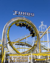 England, East Sussex, Brighton, Turbo rollercoaster amusement ride on Brighton Pier with the cars full of people upside down at the top of a loop.