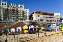 England, East Sussex, Brighton, Young people playing beach volleyball on sand on the seafront with the De Vere Grand Hotel and The Brighton Centre beyond.