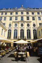GERMANY, Saxony, Dresden, The Baroque courtyard of the 18th Century Coselpalais in Neumarkt square now a restaurant and cafe busy with diners at lunchtime seated at tables under umbrellas.