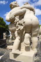 GERMANY, Saxony, Dresden, Statue seen from behind of two fat naked figures walking with their arms around each other in the restored Baroque Zwinger Palace Gardens.
