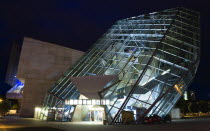 GERMANY, Saxony, Dresden, The angular structure in glass and steel of the 1999 Ufa Palast cinema designed by Austrian architecture firm Coop Himmelblau illuminated at night.