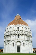 ITALY, Tuscany, Pisa, The Campo dei Miracoli or Field of Miracles.The Baptsitry with tourists on the grass with a blue sky.