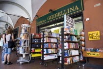 ITALY, Tuscany, Pisa, Two women looking at books ina display outside a bookshop underneath an arched walkway.