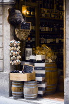 ITALY, Tuscany, Siena, Shop doorway display of Chianti wines and pasta with a stuffed wild boar head on the wall.