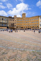 ITALY, Tuscany, Siena, Piazza del Campo and surrounding buildings under a blue sky and busy with tourists.