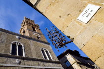 ITALY, Tuscany, Pienza, Val D'Orcia Piazza Pio II with Palazzo Communale Town Hall with its campanile belltower with an ancient lantern holder set into the corner of a wall.