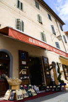 ITALY, Tuscany, Montalcino, Val D'Orcia Brunello di Montalcino Enoteca or wine shop with dispaly of boxed wines on the pavement around its entrance beneath a sunshade.