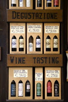 ITALY, Tuscany, Montalcino, Val D'Orcia Brunello di Montalcino Enoteca or wine shop with dispaly of boxed wines with a wine tasting sign with prices in Euros.