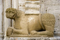 ITALY, Tuscany, San Quirico D'Orcia, The Collegiata Church of the saints Quirico and Giulitta. Sandstone carving of a lion, ossibly Etruscan, at the base of a caryatid or zoomorphic column at the entr...