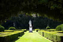 ITALY, Tuscany, San Quirico D'Orcia, The 16th Century Horti Leonini formal gardens by Diomede Leoni seen through an archway of greenery with the 1688 statue of Cosimo III de Medici.