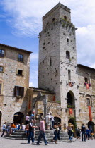 ITALY, Tuscany, San Gimignano, Tourists gathering at the well in Piazza della Cisterna in front of one of the hill towns's medieval towers.