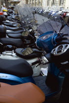 ITALY, Tuscany, Florence, Moped scooters parked in side street with a chef in uniform standing on the pavement sidewalk using a mobile cell phone.