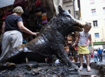 ITALY, Tuscany, Florence, People by the 17th century bronze fountain called Il Porcellino in the Mercato Nuovo also known as the Straw Market where the snout of the wild boar shines where people rub i...