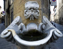 ITALY, Tuscany, Florence, Oltrarno District Drinking water fountain with gargoyle on corner building in Piazza de'Frescobaldi designed by Buontalenti in the 16th Century with narrow streets on either...
