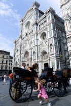ITALY, Tuscany, Florence, The Neo-Gothic marble west facade of the Cathedral of Santa Maria del Fiore the Duomo with a sightseeing tourist family getting out of a horsedrawn carriage.