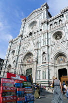 ITALY, Tuscany, Florence, The Neo-Gothic marble west facade of the Cathedral of Santa Maria del Fiore the Duomo with sightseeing tourists sitting on the steps and guidebooks in different languages at...