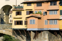 ITALY, Tuscany, Florence, Ponte Vecchio medieval bridge across River Arno. View of merchant's shops that line bridge and hang over the water below.