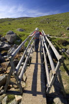 IRELAND, County Wicklow, A hiker crosses a wooden bridge on the Spink Trail. 