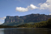 VENEZUELA, Bolivar State, Canaima National Park, A big Tepui mountain by the coast of a river shoot on a bright day with blue sky and white clouds