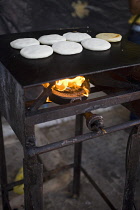 VENEZUELA, Bolivar State, Ciudad Bolivar, Handmade pancakes on a metal big plate with fire underneath them are being baked, at the street of Ciudad Bolivars historical centre.