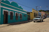 VENEZUELA, Bolivar State, Ciudad Bolivar, Colorful, candy like, buildings and an old American car in front of them shoot on a bright day with blue sky at Ciudad Bolivars old historical centre.